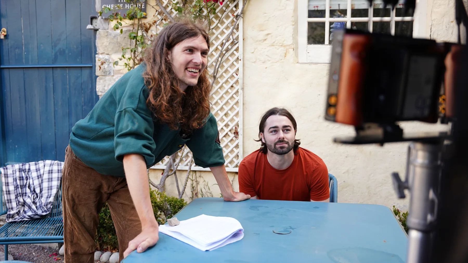 Crew members discussing a scene beside an outdoor table and camera