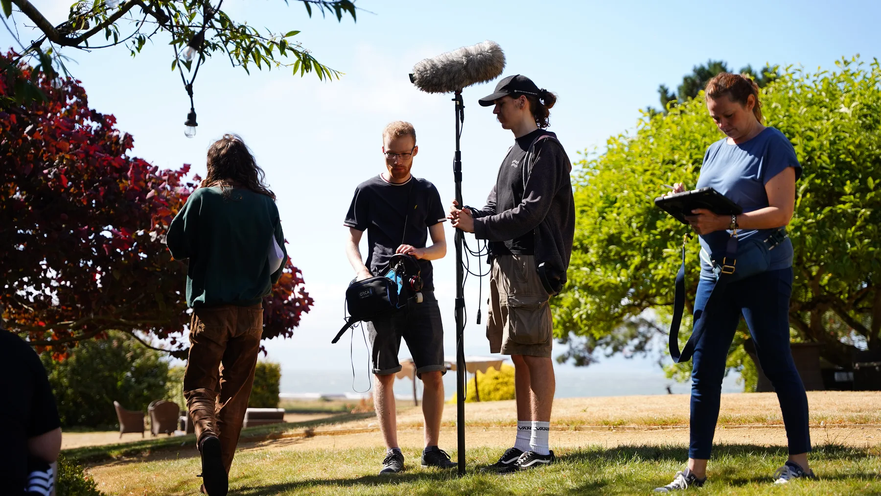Production crew working with a boom microphone and monitors outdoors