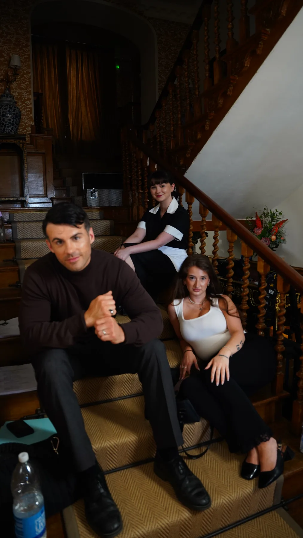 Cast members relaxing together on the manor staircase