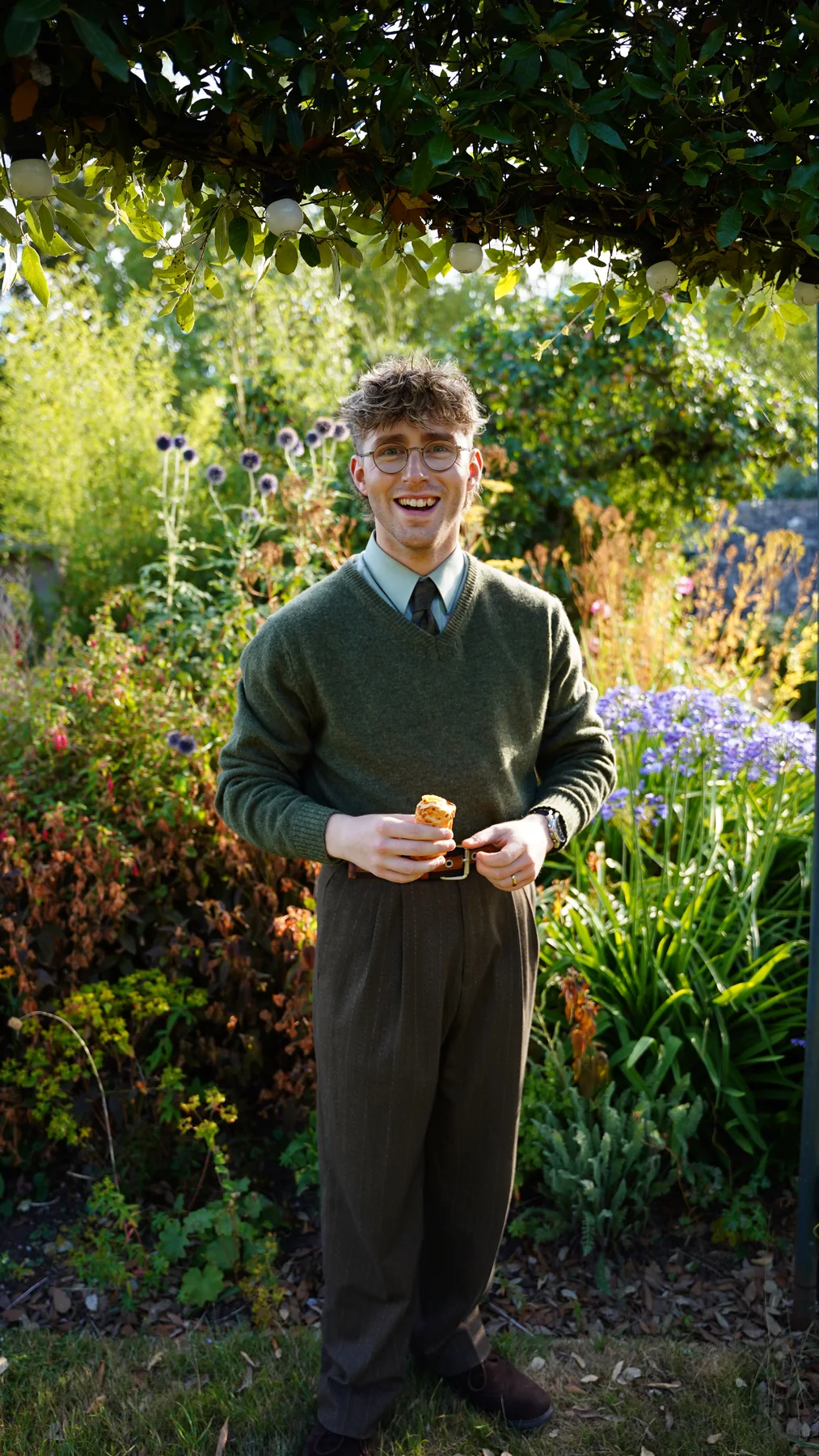 Cast member in a green jumper taking a break in the garden