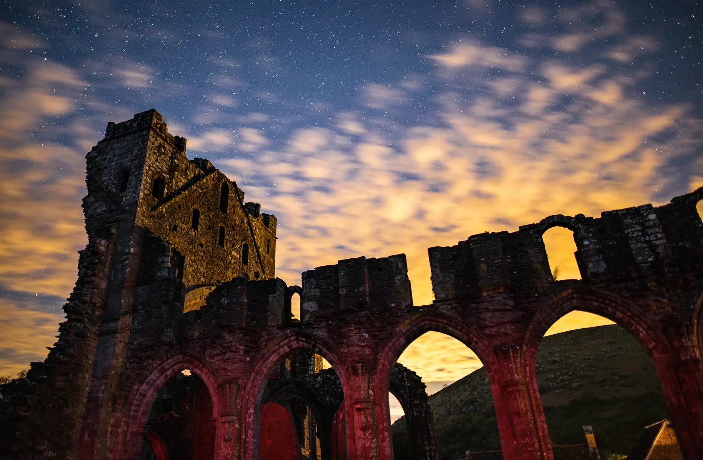 Illuminated priory ruins beneath a starry night sky